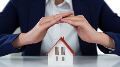 Unsere Fachleute unterschiedlicher Disziplinen sorgen dafür, dass in den Gebäuden unserer Nutzer*innen alles rund läuft. Frau hält ihre Hände schützend über ein Haus.